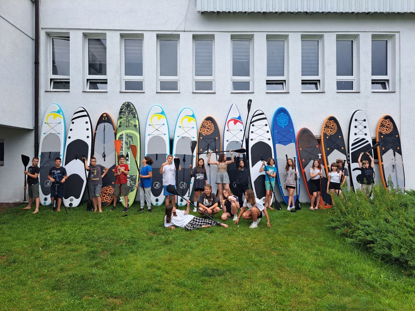 Grupa dzieci z deskami SUP przed ośrodkiem